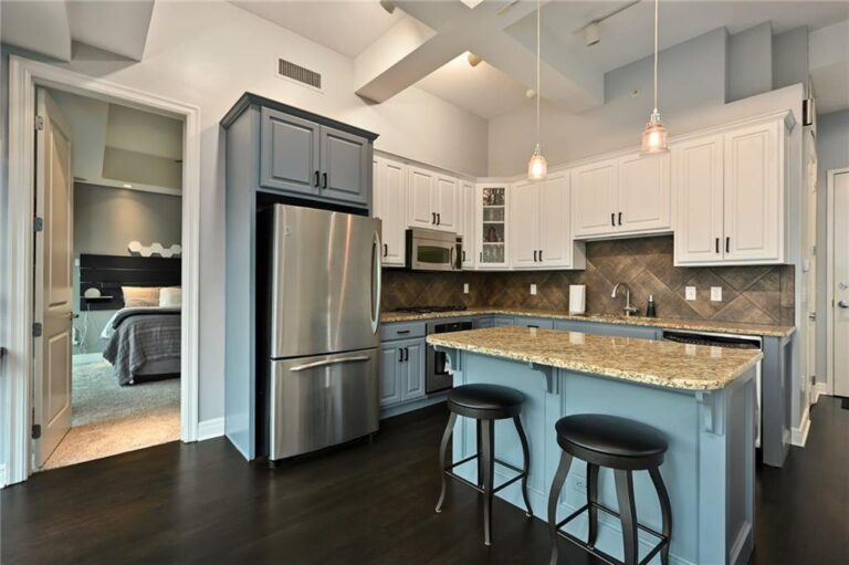 Kitchen with white upper cabinets, stainless refrigerator and pendant lights over the island, Wallstreet Towers, downtown Kansas City, MO