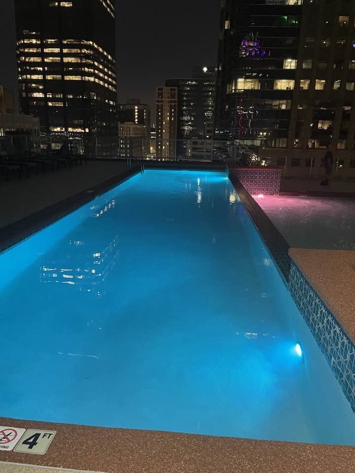 Lit rooftop pool at night surrounded by downtown towers, Wallstreet Towers, downtown Kansas City, MO
