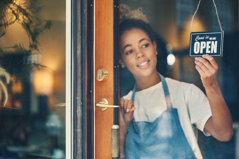 a woman holding the open store signage