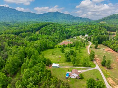 Versatile 17.6-acre property for sale in Columbus, North Carolina, featuring a four-bedroom home, mountain views, creek, pool, workshop, and unrestricted land suitable for horses or livestock.