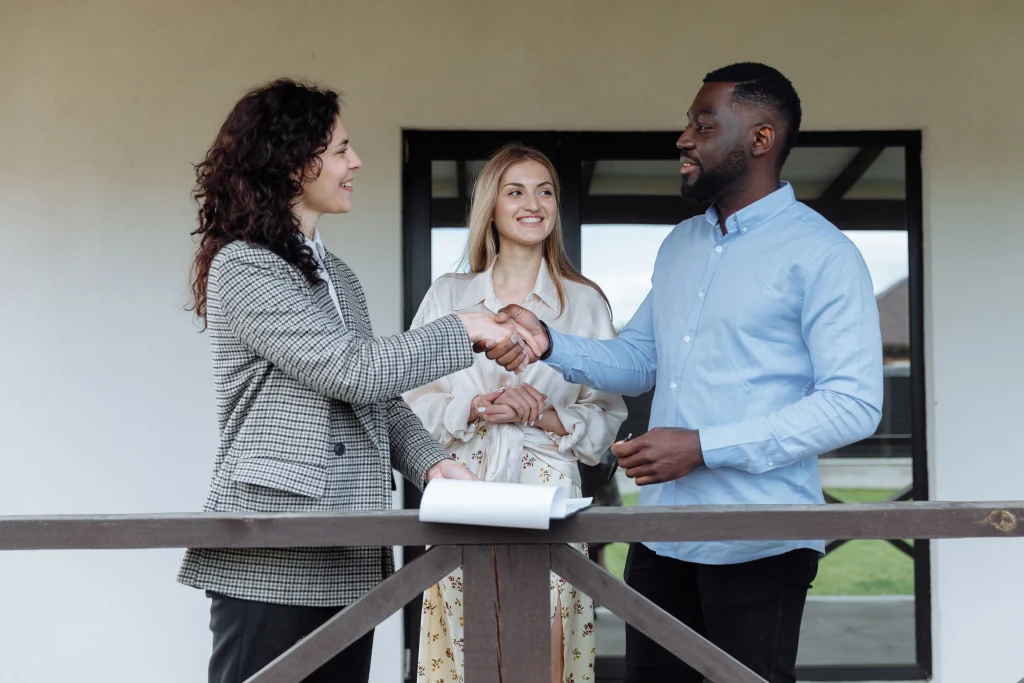 two real estate agents shaking hands while client is in the back