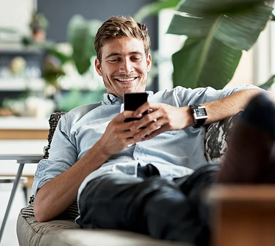 Man on couch holding phone, smiling