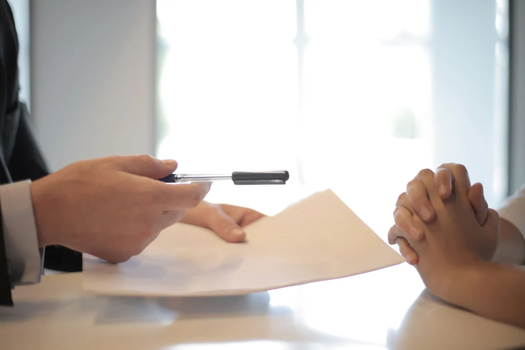 Hands handing over paper and pen to other set of hands