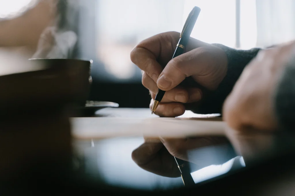 Hand holding pen writing letter of intent