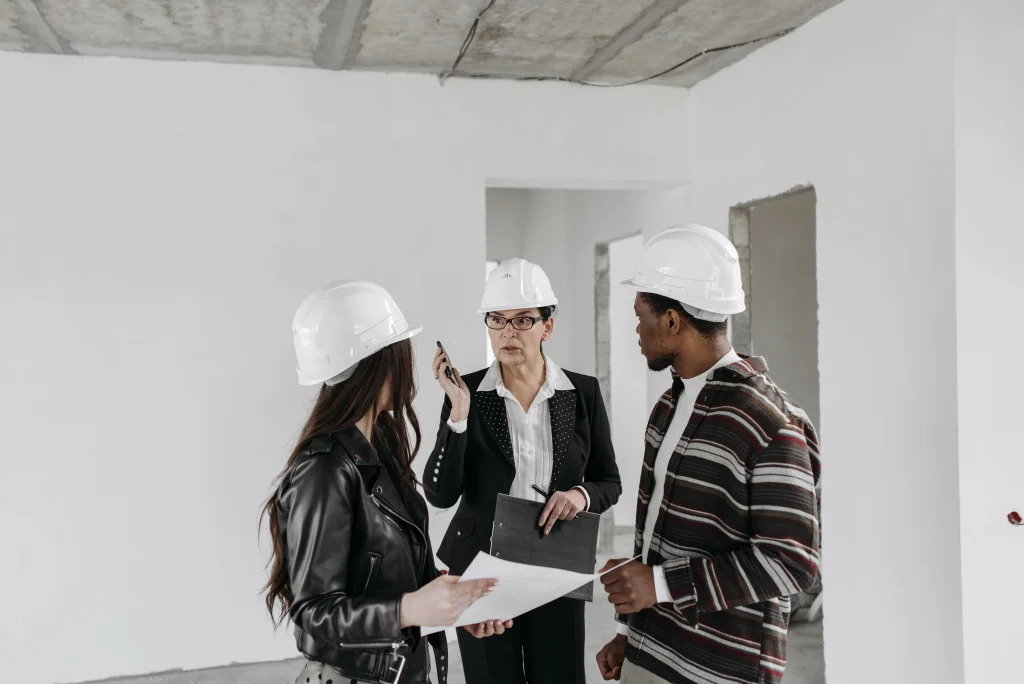 Real Estate and builder talking with hard hats on.