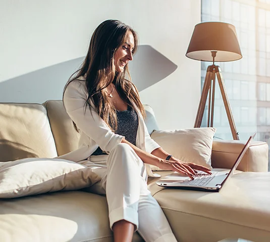 Real Estate Agent sitting on couch viewing a computer