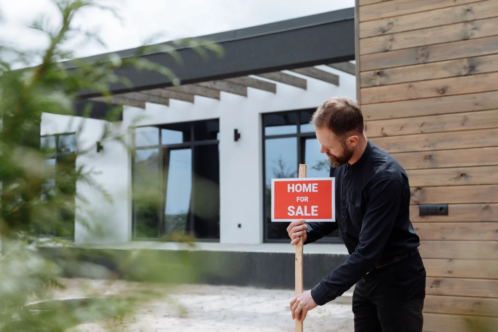 Real Estate Agent putting up for sale sign outside a house