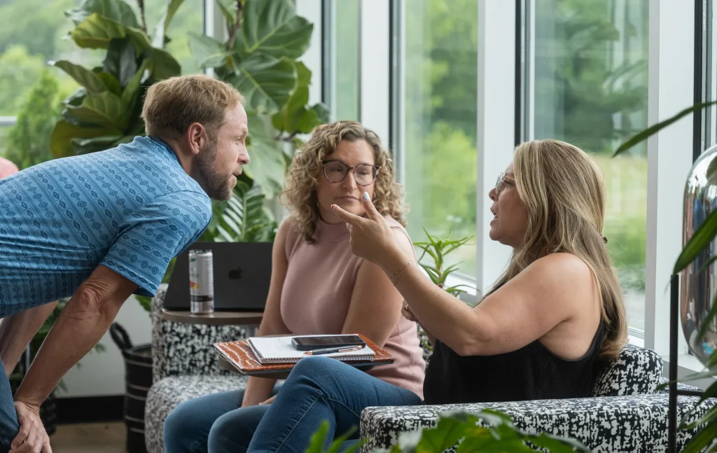 Real Estate Agent conversing with 2 people on a couch