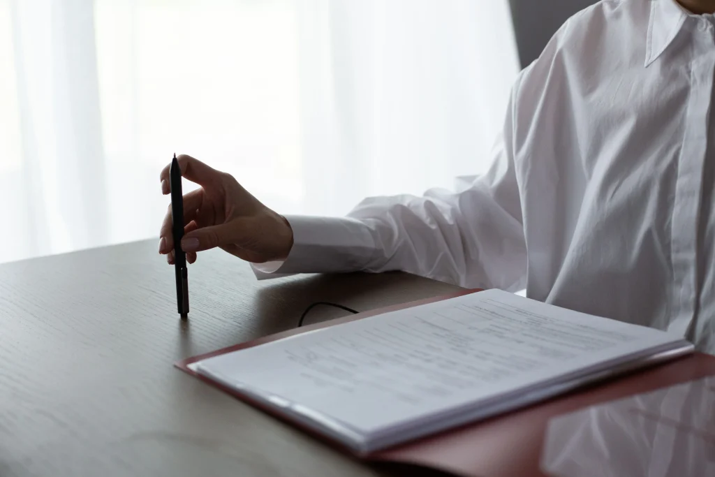 Table with documents with hand holding pen
