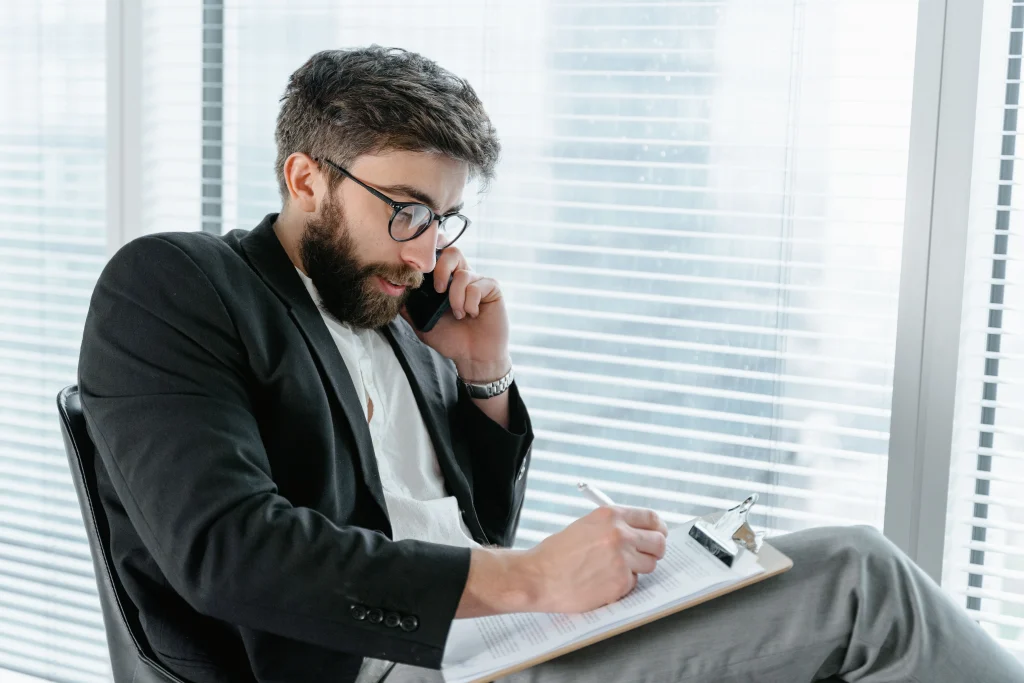 Man recieving phone call while writing on notepad