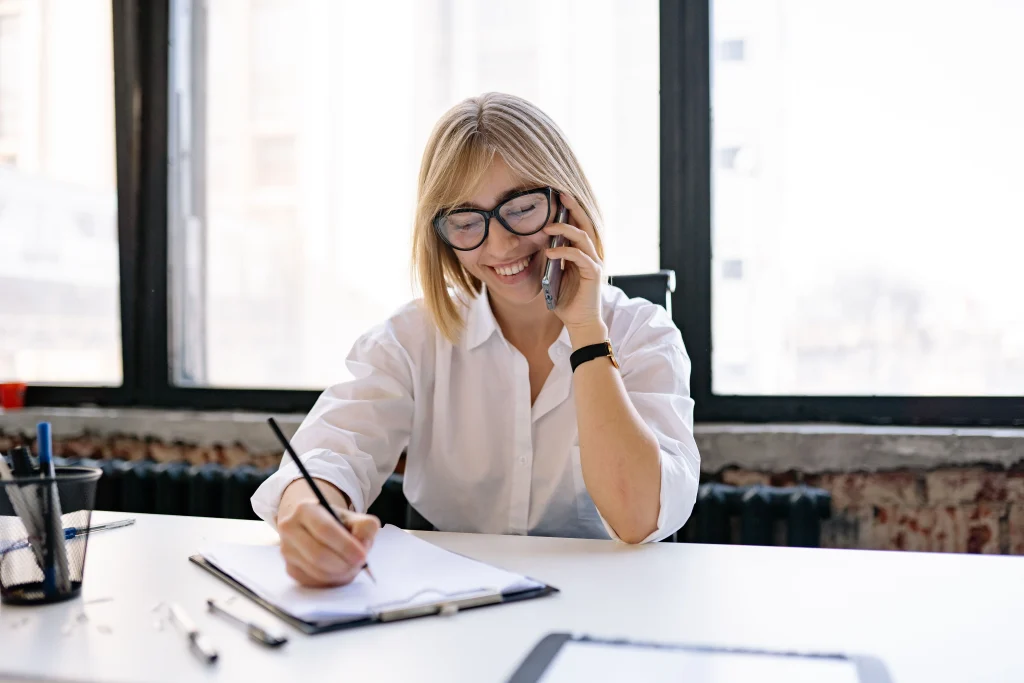 Receptionist taking a call at a desk and taking notes
