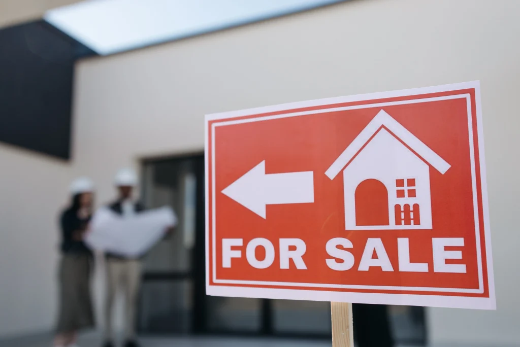 For Sale sign with house in the background