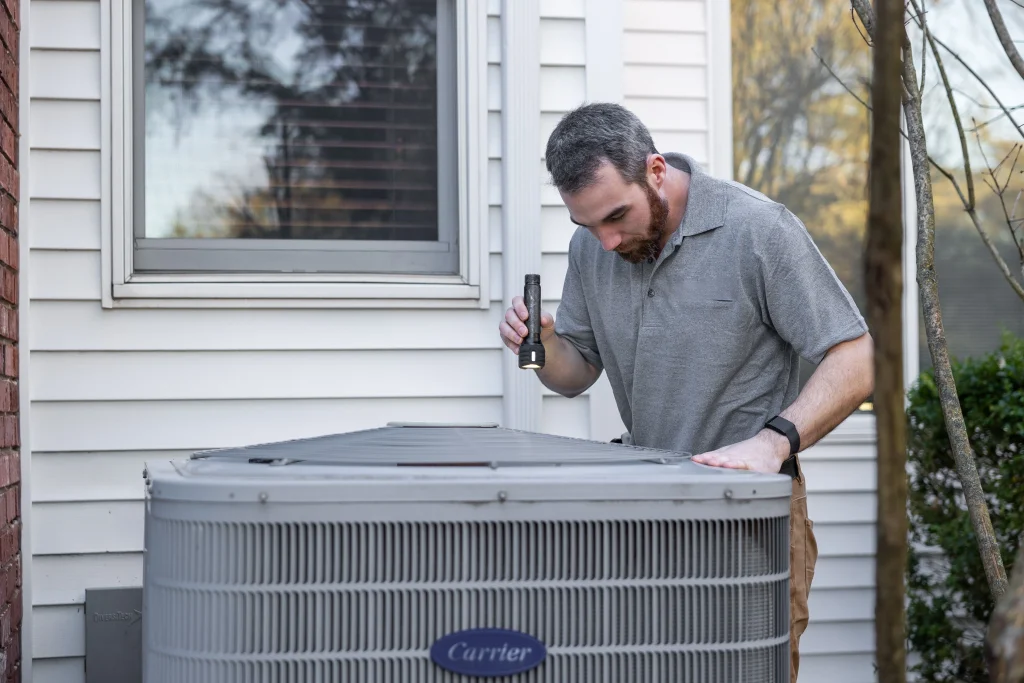 HVAC working inspecting AC unit