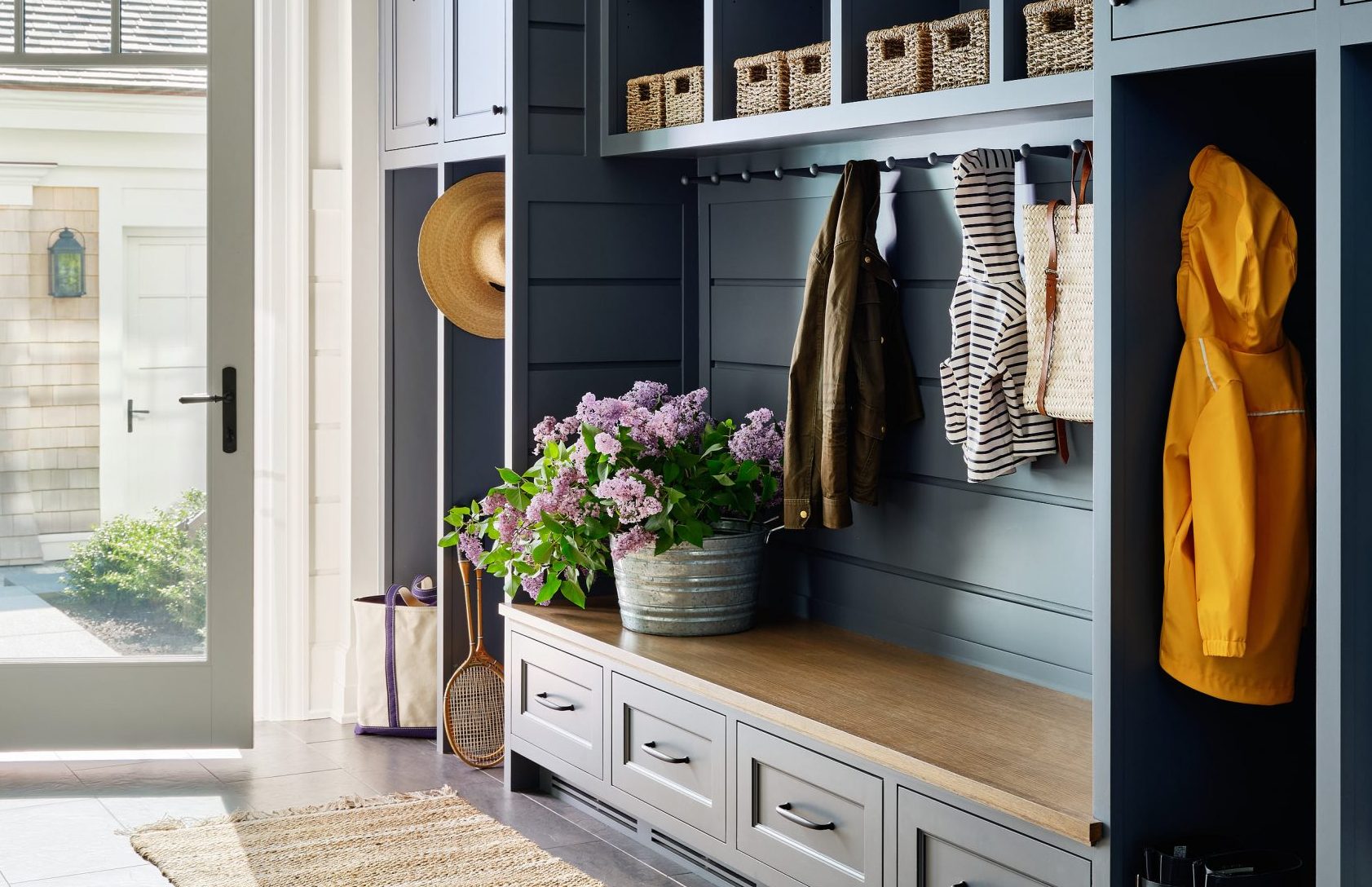 Built-in mudroom storage with bench seating, hooks for coats, cubbies with baskets, drawers, and organized entryway design in a modern new construction home.