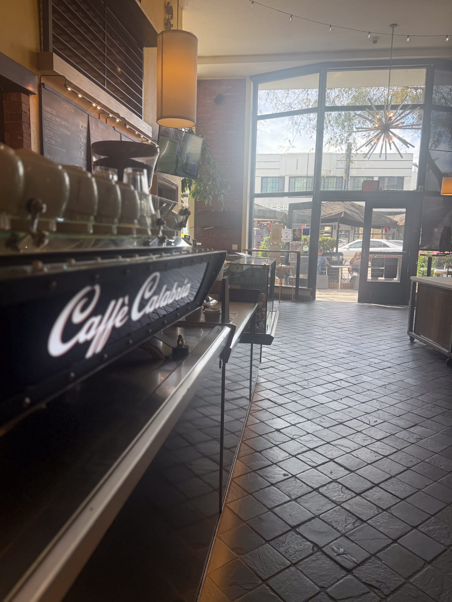 Caffe Calabria branded espresso machine with view of 30th Street through large windows in North Park San Diego