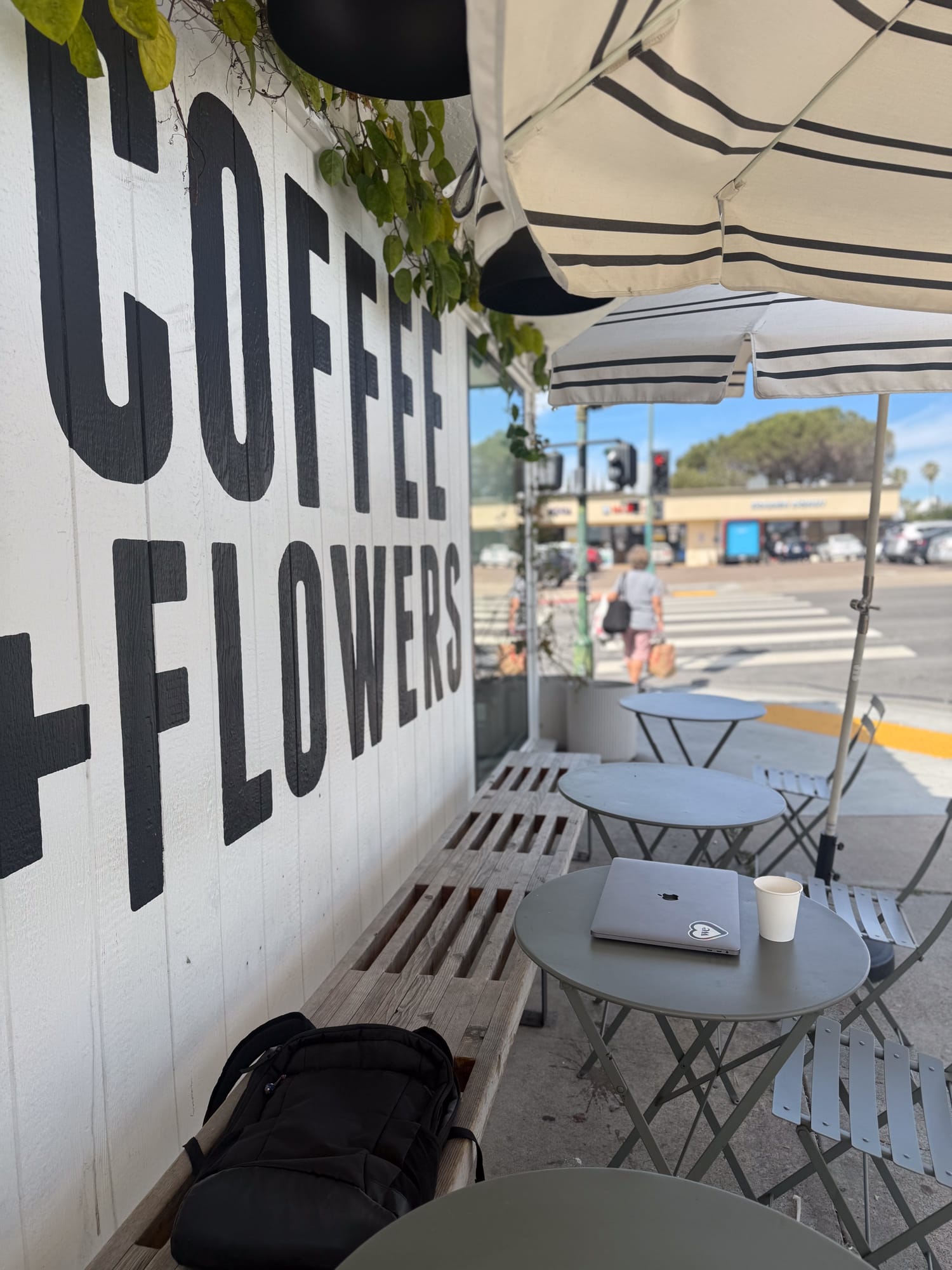 Coffee and Flowers sign on Communal Coffee patio with striped umbrellas and sidewalk tables in North Park San Diego