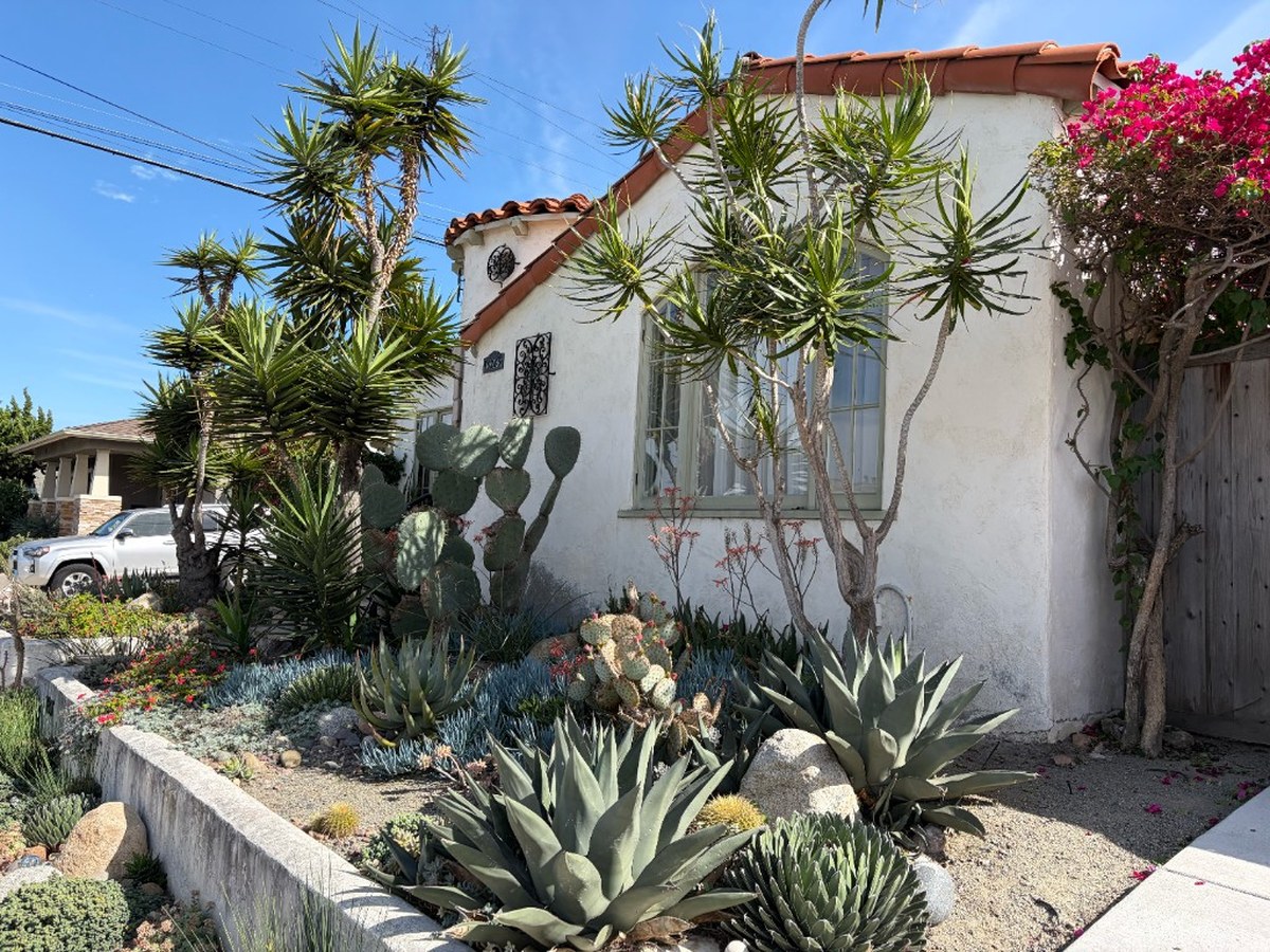 Spanish-style San Diego home with drought-tolerant front yard landscaping featuring agave, yucca, and native succulents — typical of walkable San Diego neighborhoods