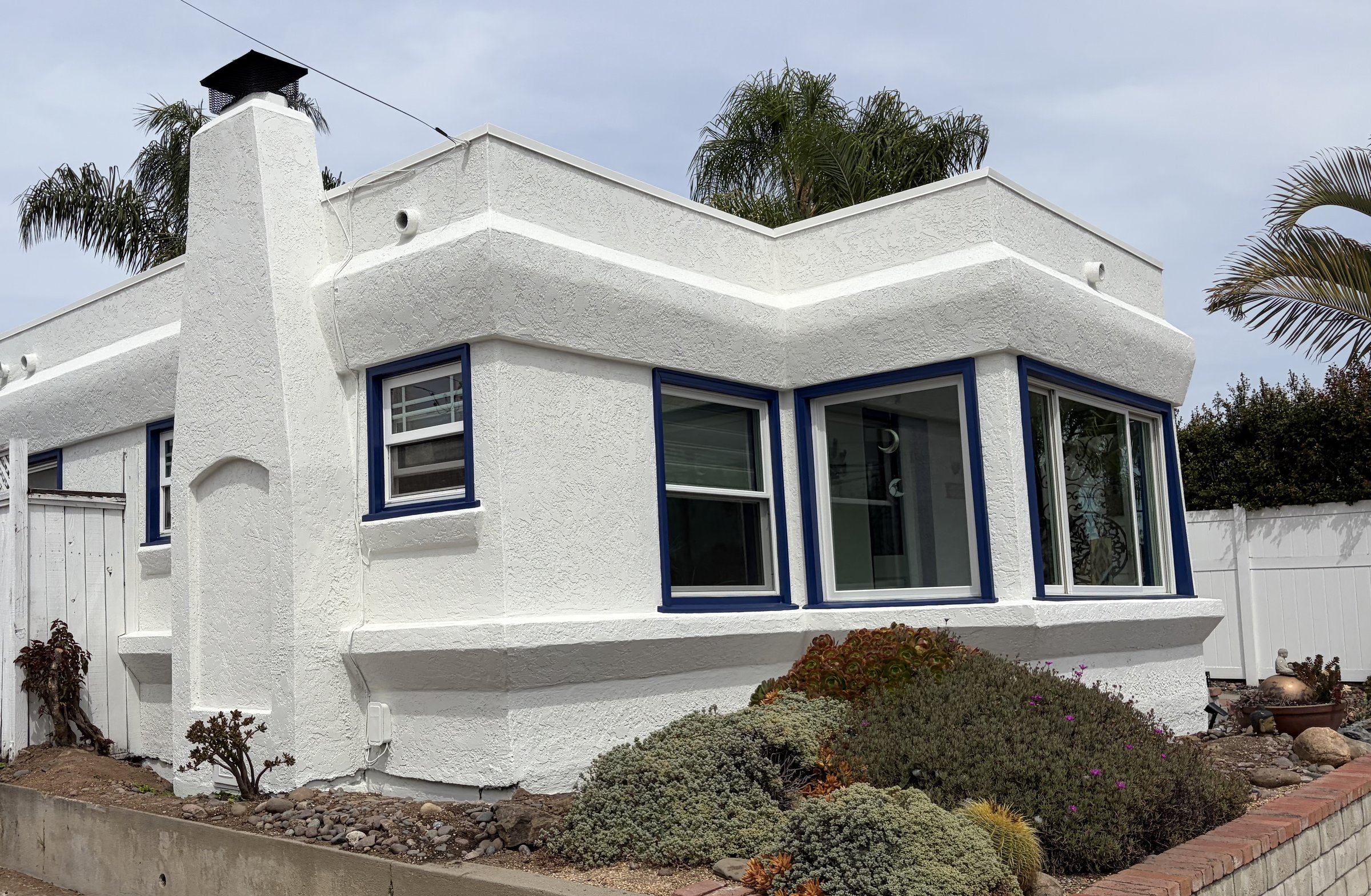 White stucco home with blue window trim and drought-tolerant landscaping in San Diego