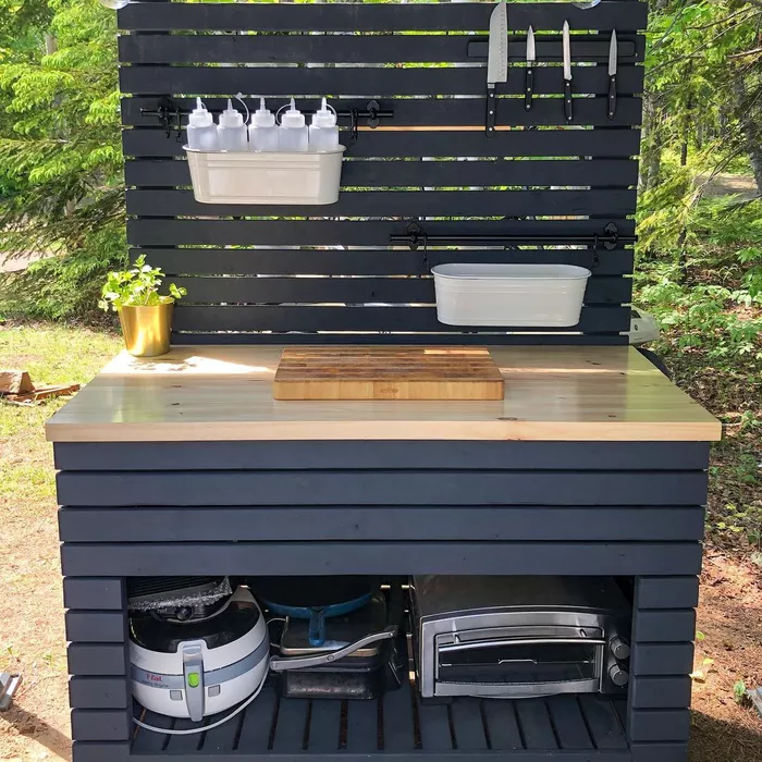 A DIY outdoor kitchen table with shelving and storage buckets.