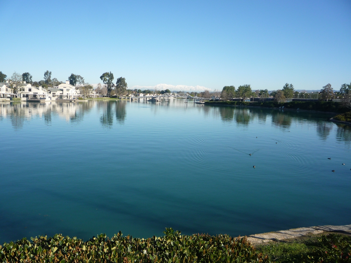 Woodbridge South Lake in Irvine with lakefront homes and a walking bridge on a clear day