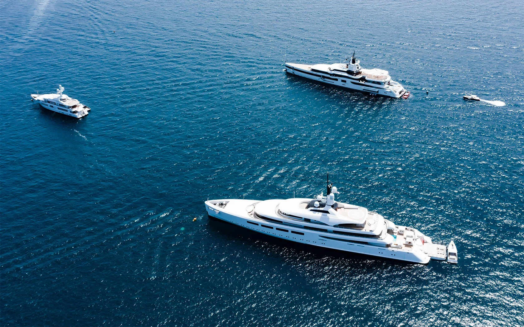 Aerial view of a marina filled with various yachts and boats docked along the piers in turquoise water.