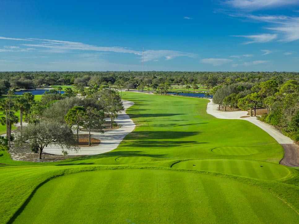 A scenic view of a golf course featuring lush green fairways, sand traps, and trees under a clear blue sky.