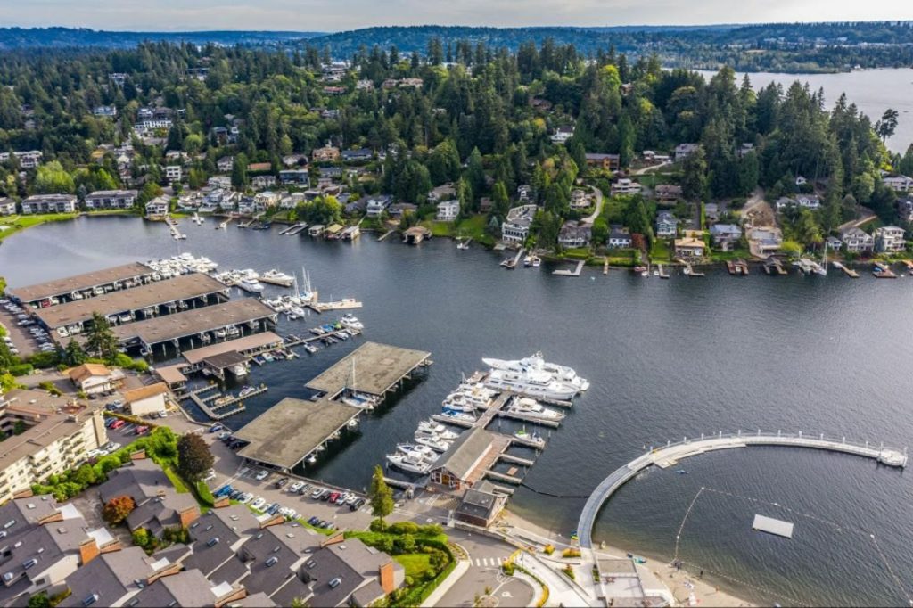 Aerial view of a marina with boats, surrounded by lush greenery and residential areas along the water's edge.