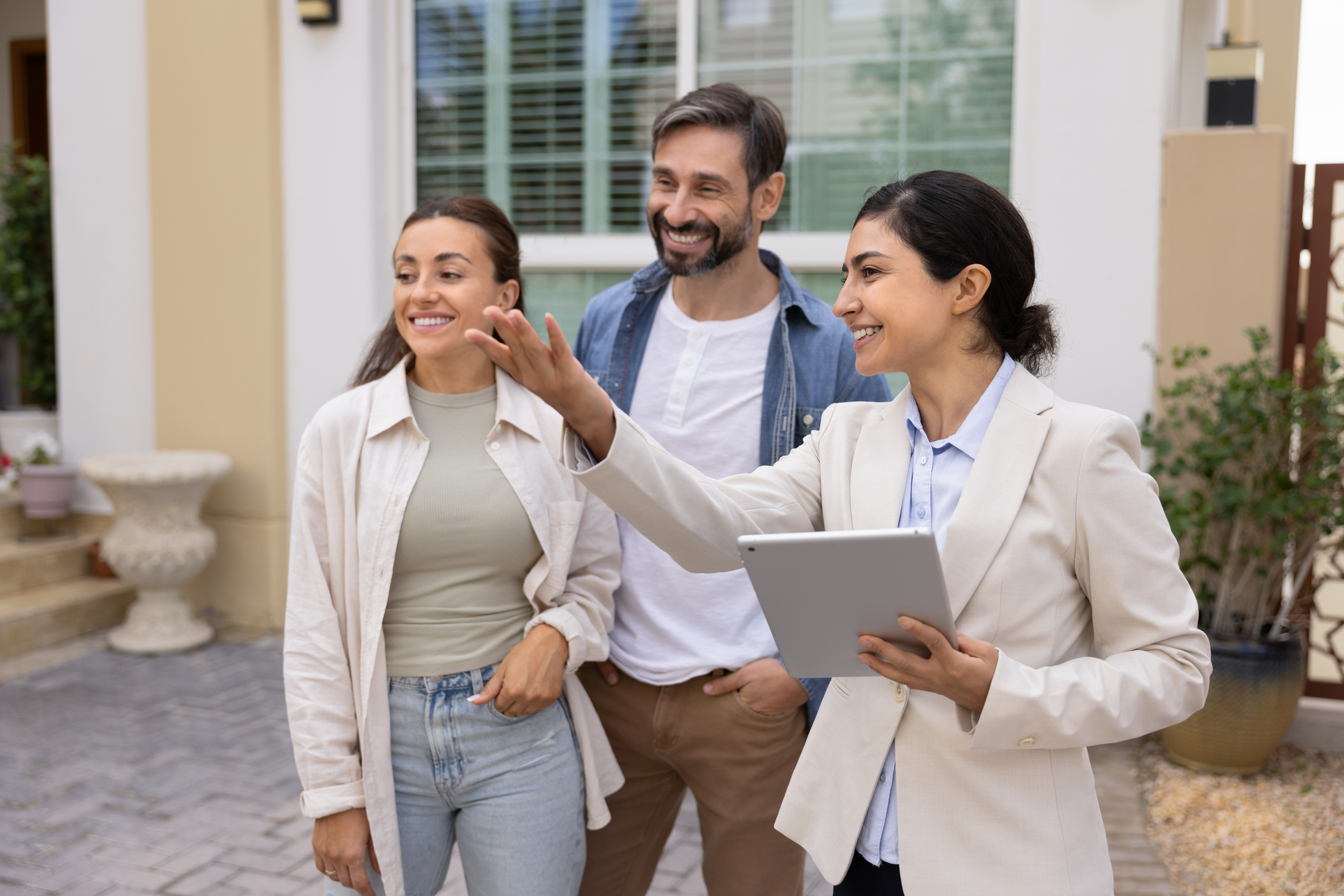 Young Indian woman real-estate agent showcasing new property for buying or renting to young Latin spouses