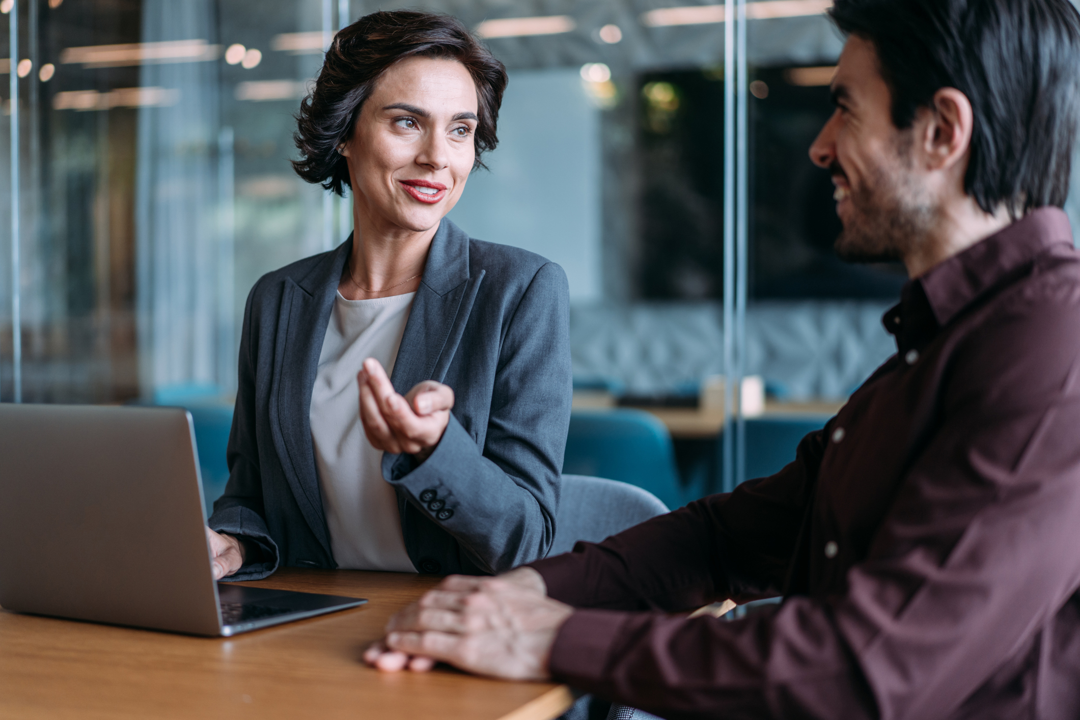 Shot of a two confident business persons sitting on a desk in the office and sharing ideas.