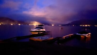 Great Sacandaga Ring of Fire campfires glowing along the shoreline at dusk