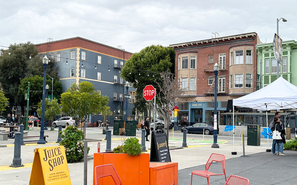 A vibrant green space in Hayes Valley with small businesses lining the street, showcasing the neighborhood's lively atmosphere.