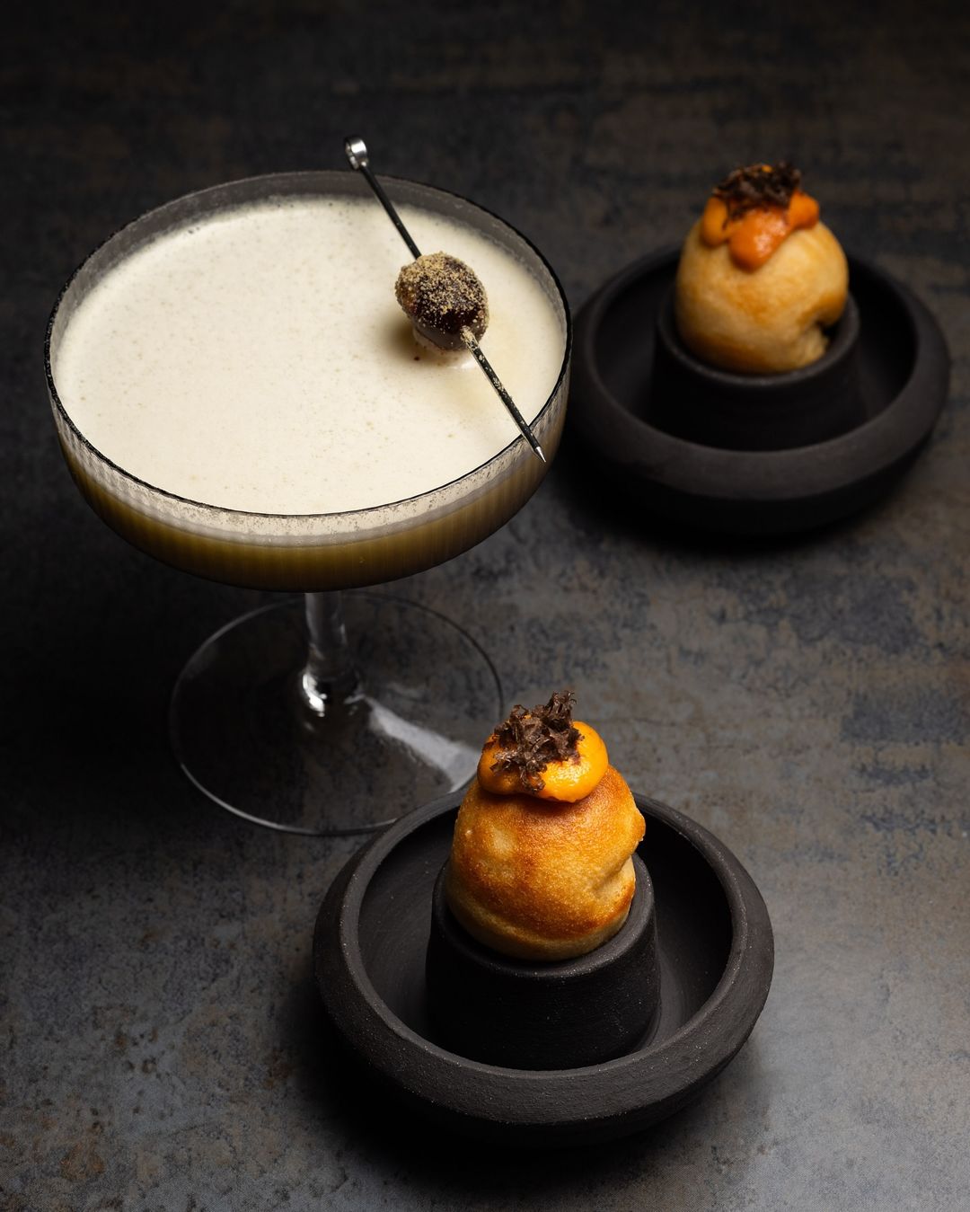 Contemporary ceramic black dishes with two amuse bouche offerings and a signature cocktail in a coupe glass from Nightbird SF