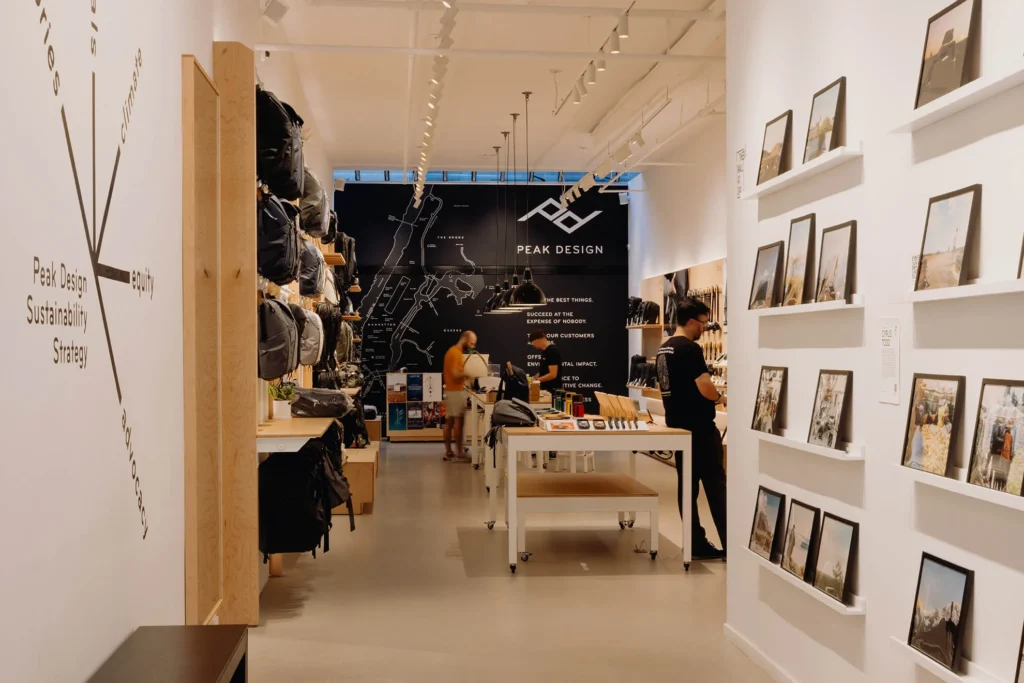 Interior View of Store with Customers Shopping, Artisan Backpacks Hanging along the wall, and photo prints available for sale at Peak Design in Hayes Valley