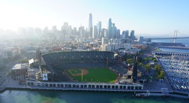 Aerial View from the waterfront of Oracle Park with the San Francisco city skyline and residential and commercial real estate buildings in the background