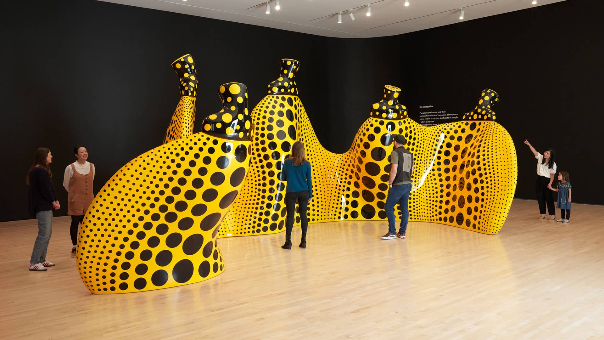 Visitors to SFMOMA admiring a large black and yellow polka dot artwork structure