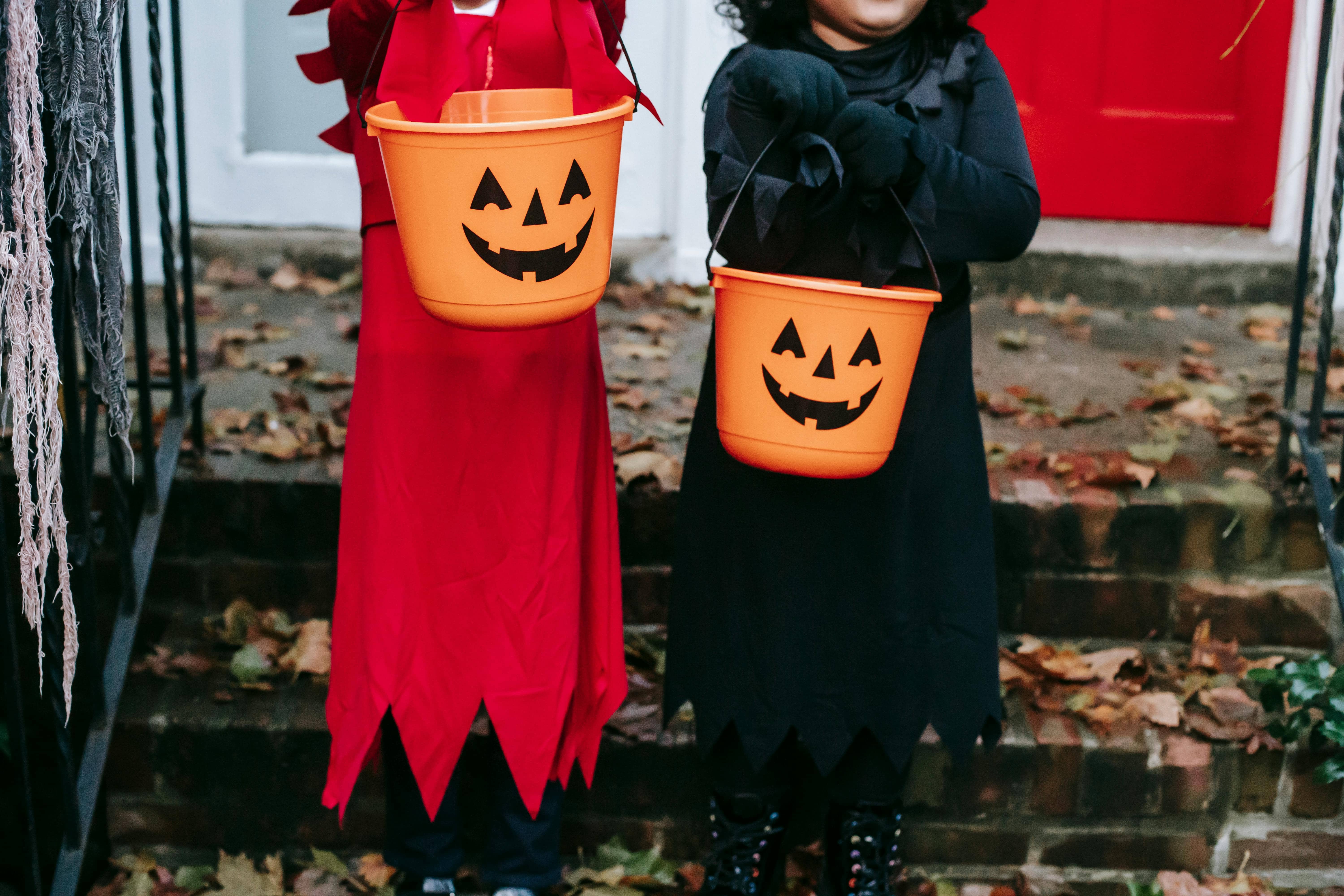 Children in Halloween costumes holding pumpkin-shaped candy buckets
