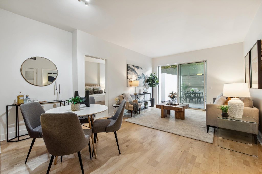 Open concept living room with dining table and couches and sliding doors to outdoor space in a luxury highrise condo sold by top SF realtor Robyn Kaufman