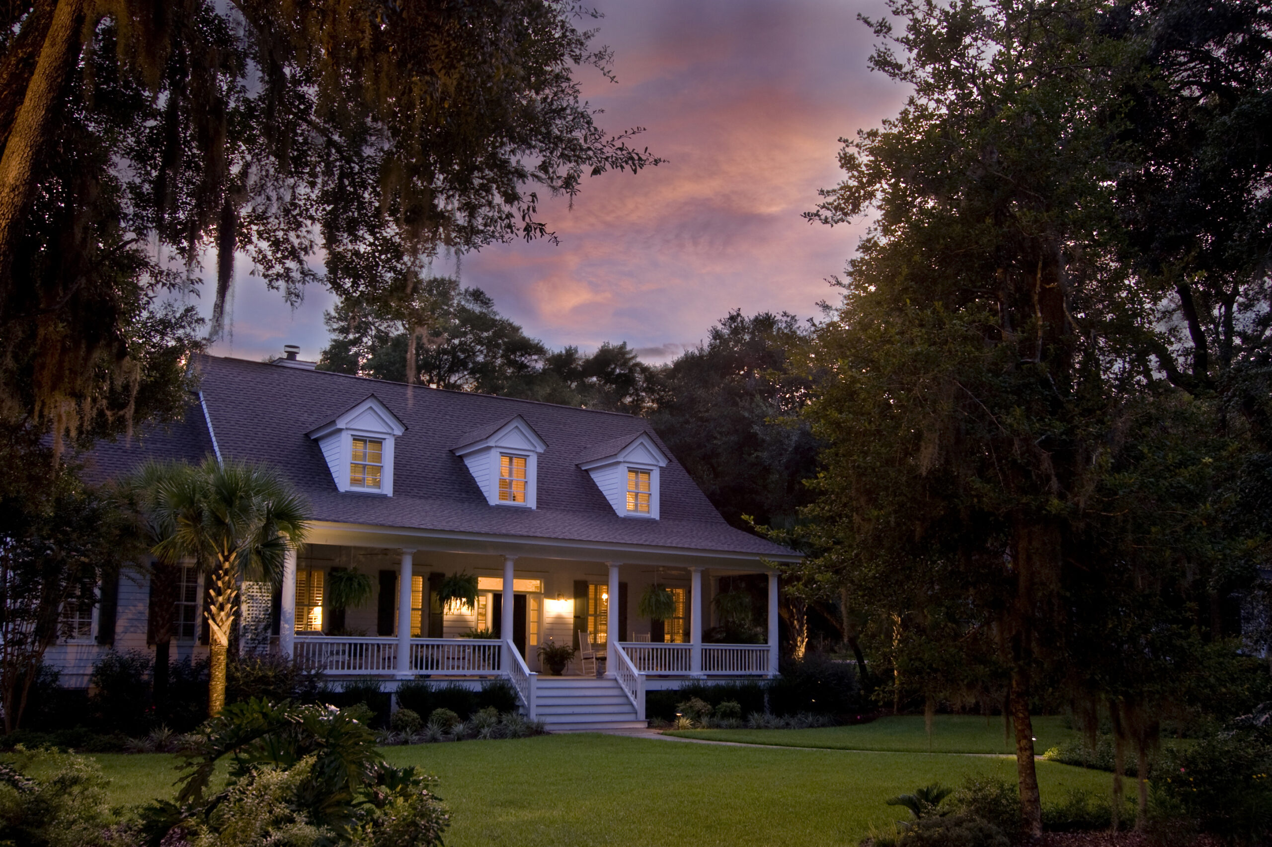 beautiful house lit up at twilight with orange clouds