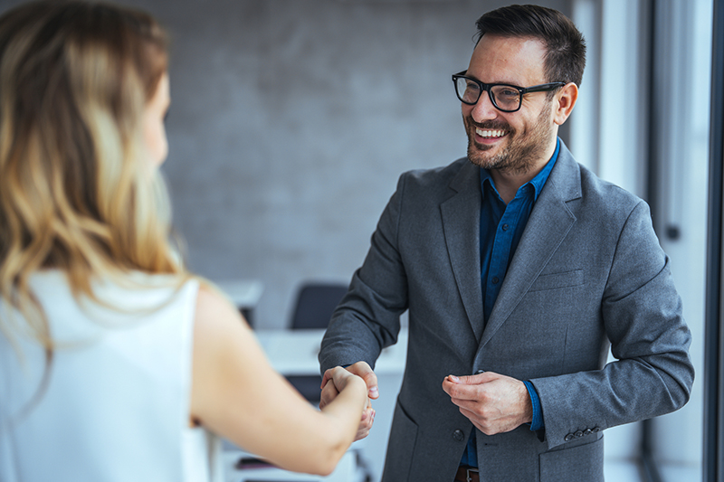 Recruiter shaking successful smiling businesswoman candidate hand at meeting