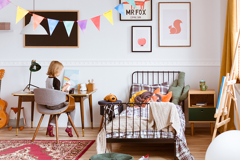 Cute little girl sitting at desk in her stylish vintage bedroom