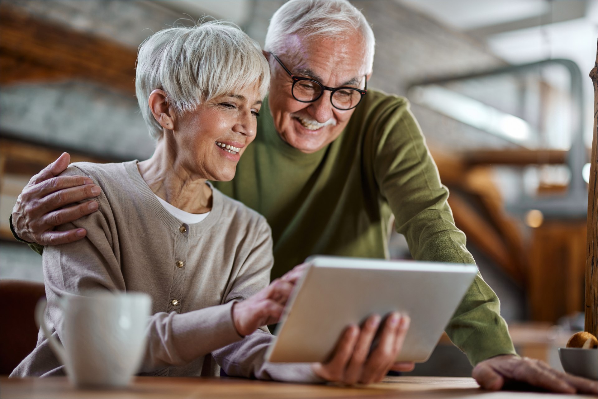 Happy mature couple enjoying while using digital tablet at home
