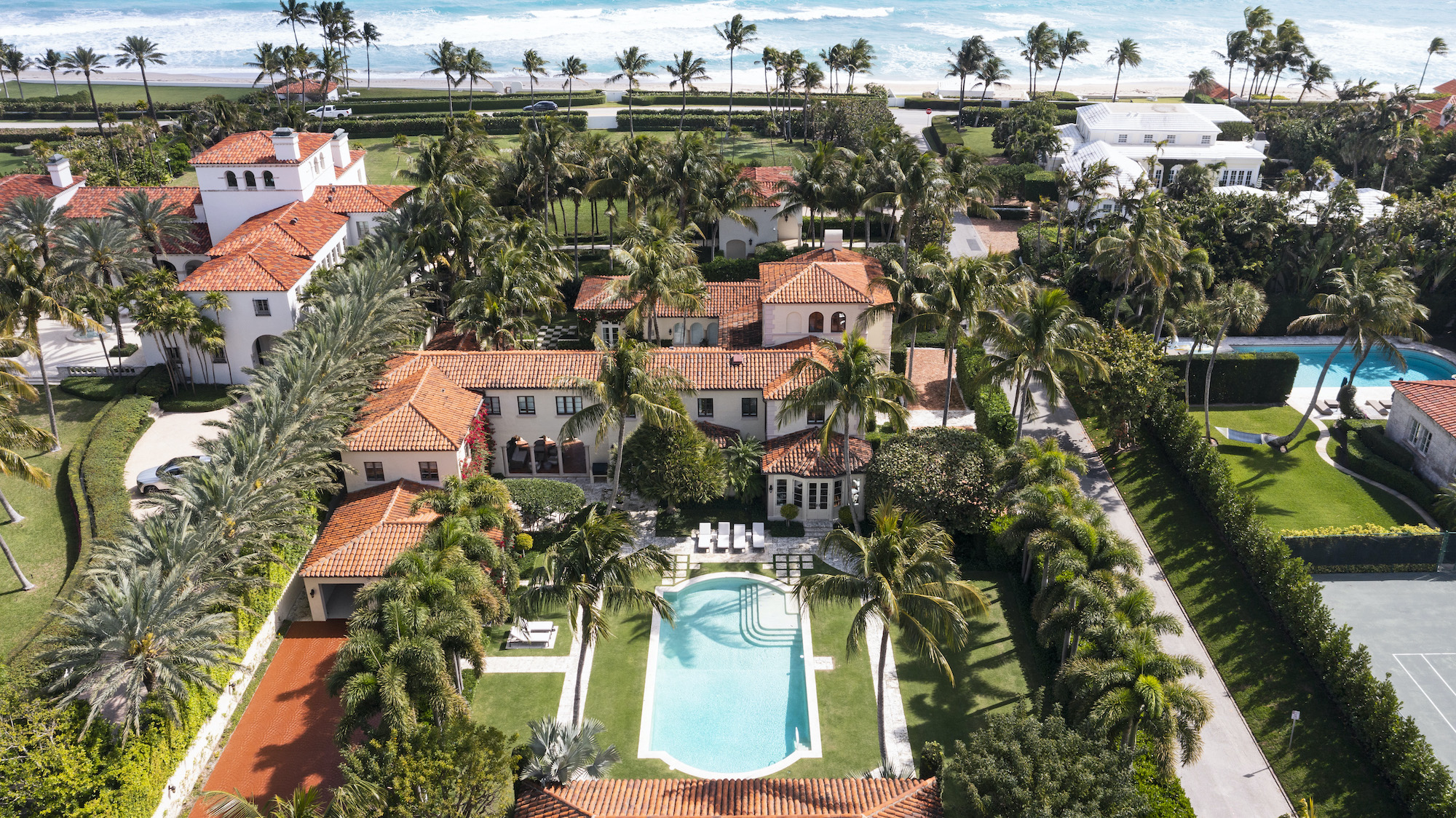 Aerial view of a Palm Beach oceanfront estate featuring Mediterranean Revival architecture, manicured grounds, and a private pool near the Atlantic Ocean.