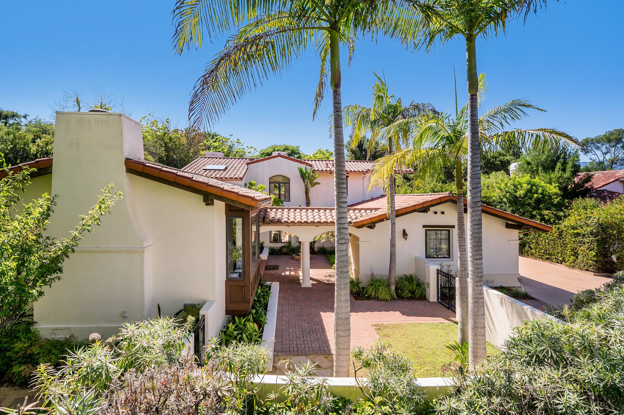 A home with palm trees and lush landscaping, featuring a front porch
