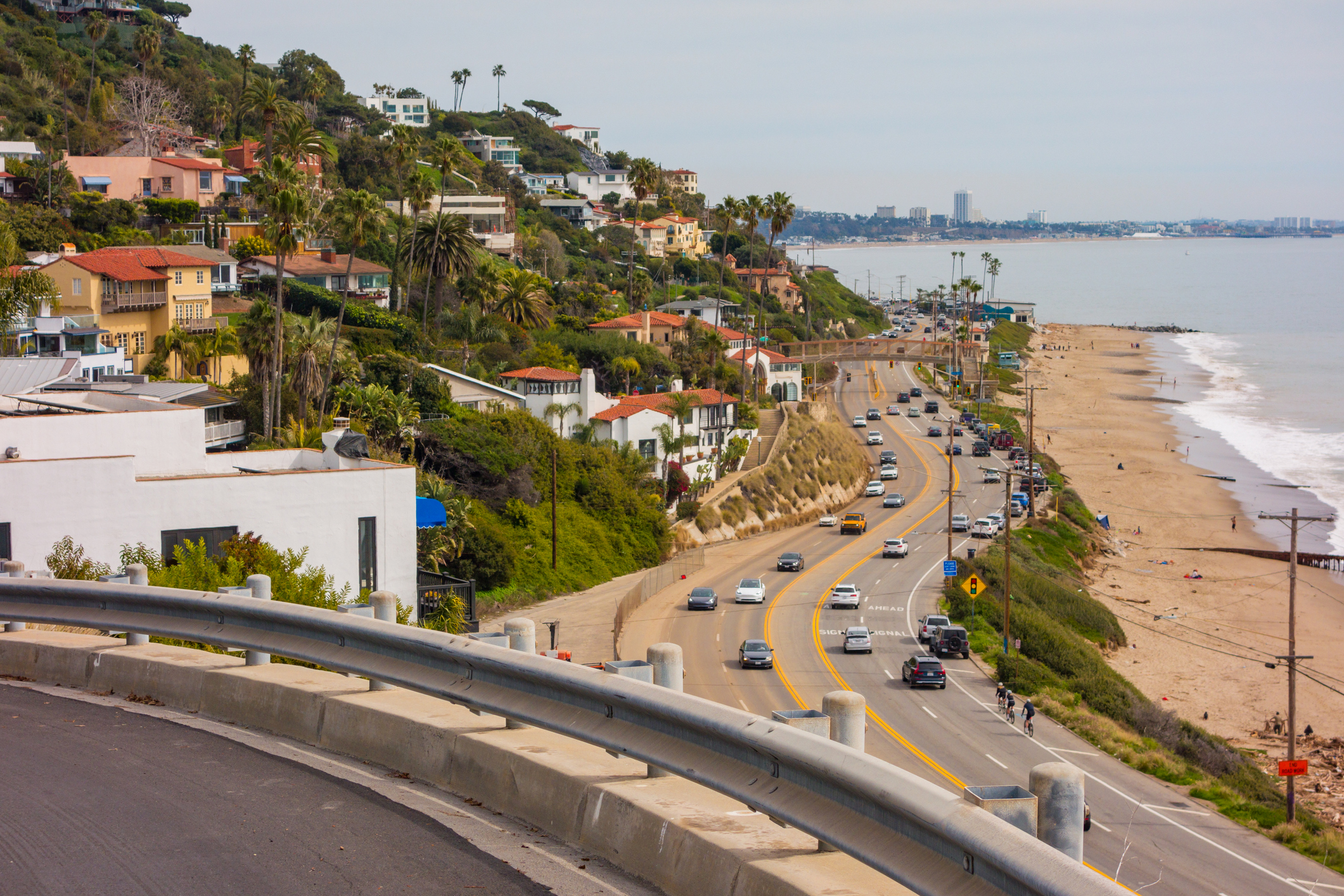 Santa Monica Mountains, filled with mansions, meeting the ocean. Looking north up the Pacific Coast Highway toward Pacific Palisades on a hazy day.