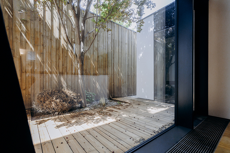 It is a view of a beautifully crafted wooden deck seen through a window