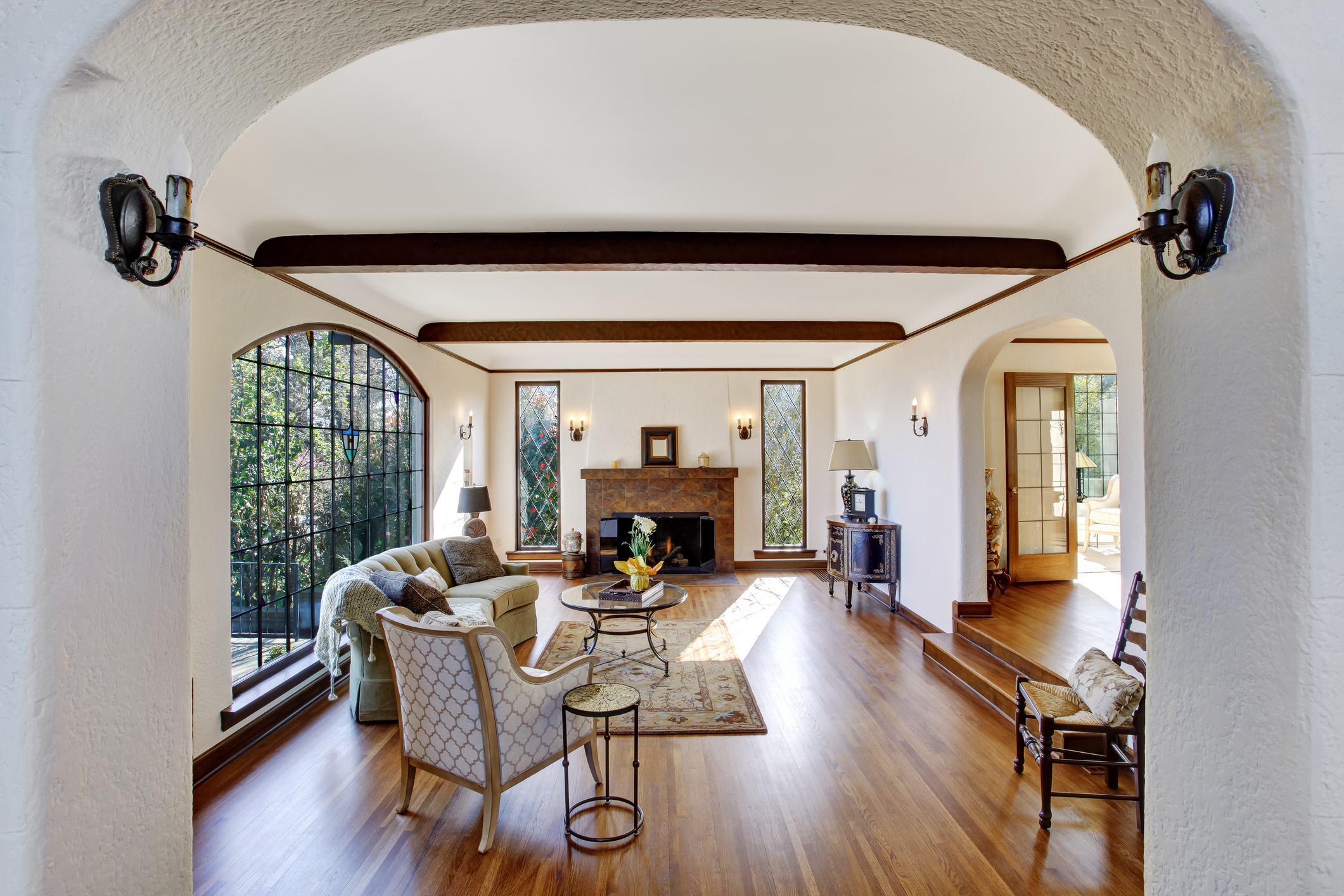 Bright living room with arch window and fireplace. View of archway