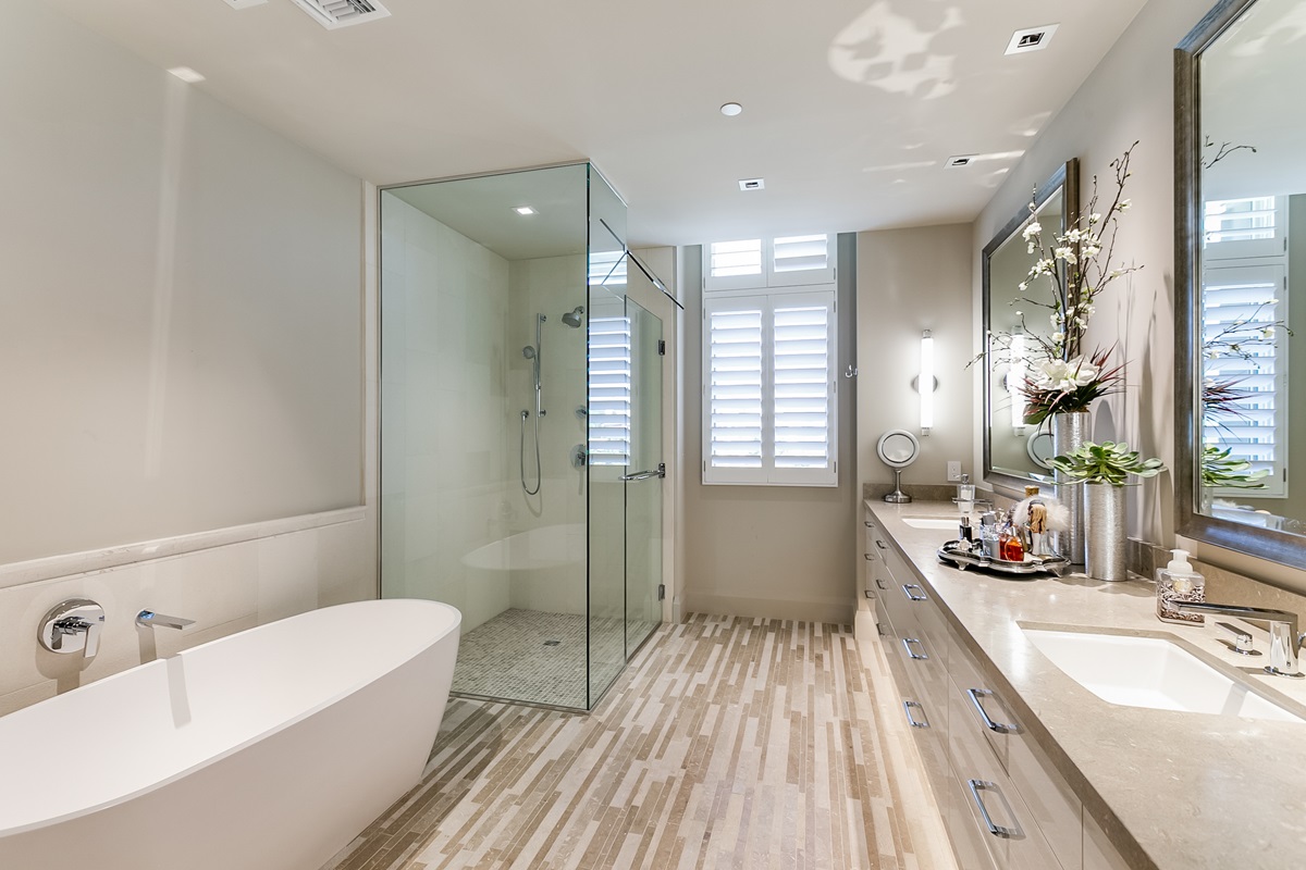 Luxurious bathroom at Icon at Silverleaf featuring a freestanding tub, glass-enclosed shower, and double vanity with large mirrors.