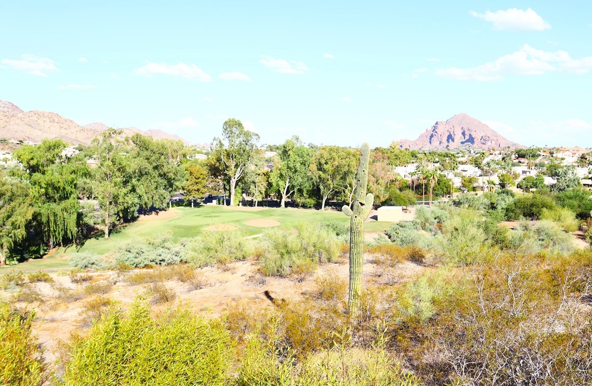 Desert golf course with views of Camelback Mountain in the background, surrounded by lush trees and desert landscape.