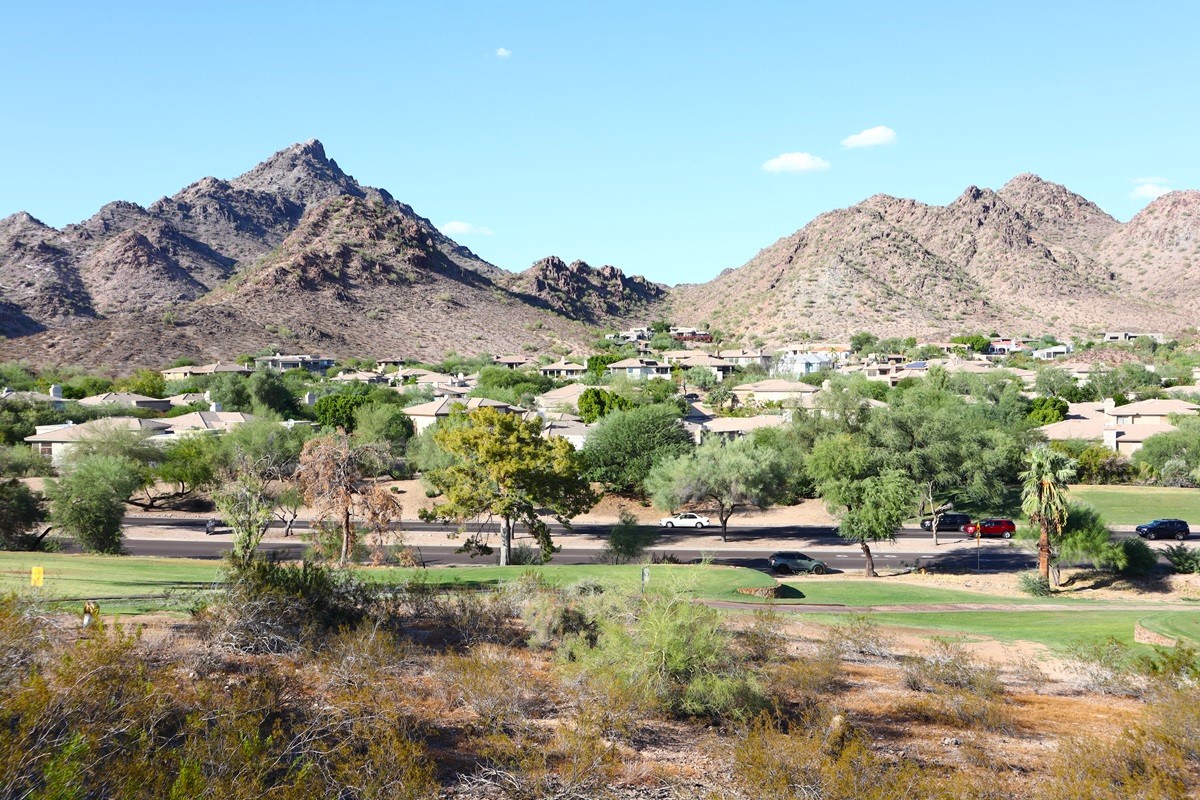 Neighborhood in the Biltmore area with desert golf course and rugged mountains in the background under a clear blue sky.