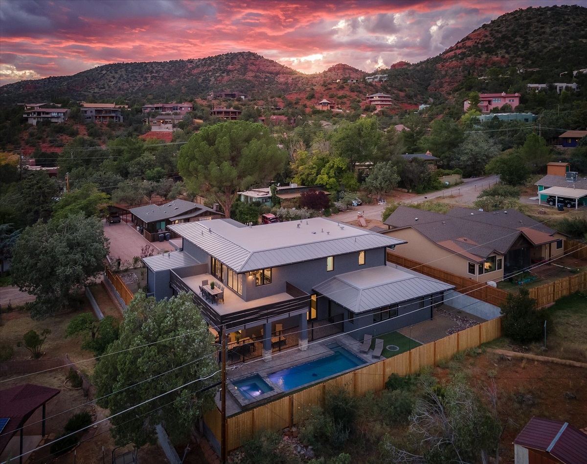 A drone shot of a luxury home at sunset with spectacular mountains in the background.